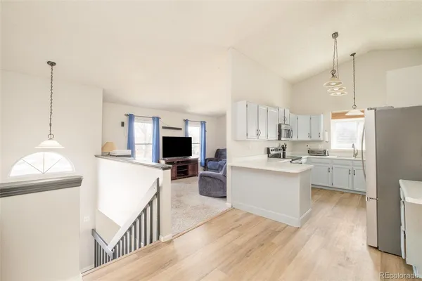 a kitchen with stainless steel appliances a stove a sink dishwasher a refrigerator white cabinets and wooden floor