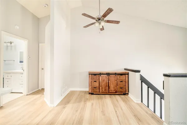 a view of a hallway with wooden floor and a ceiling fan