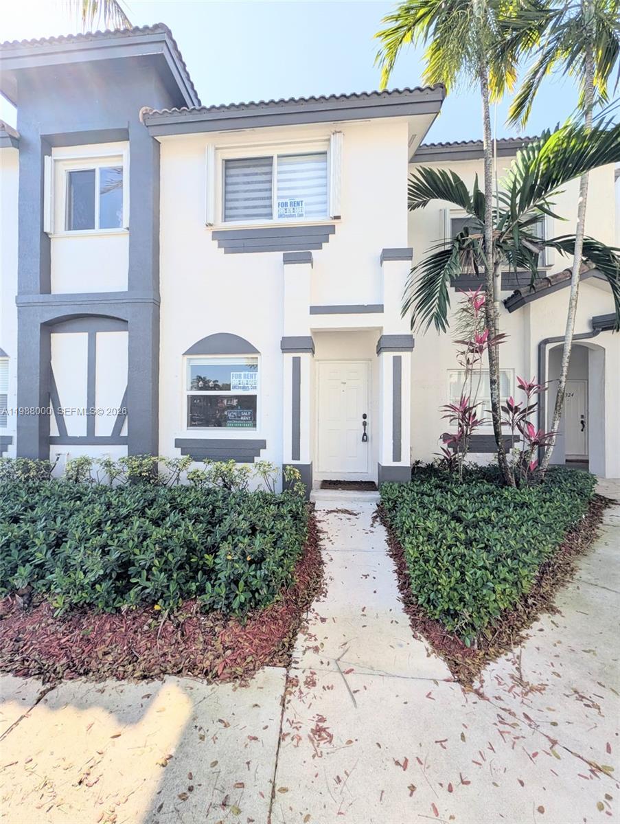 a front view of a house with a yard and potted plants