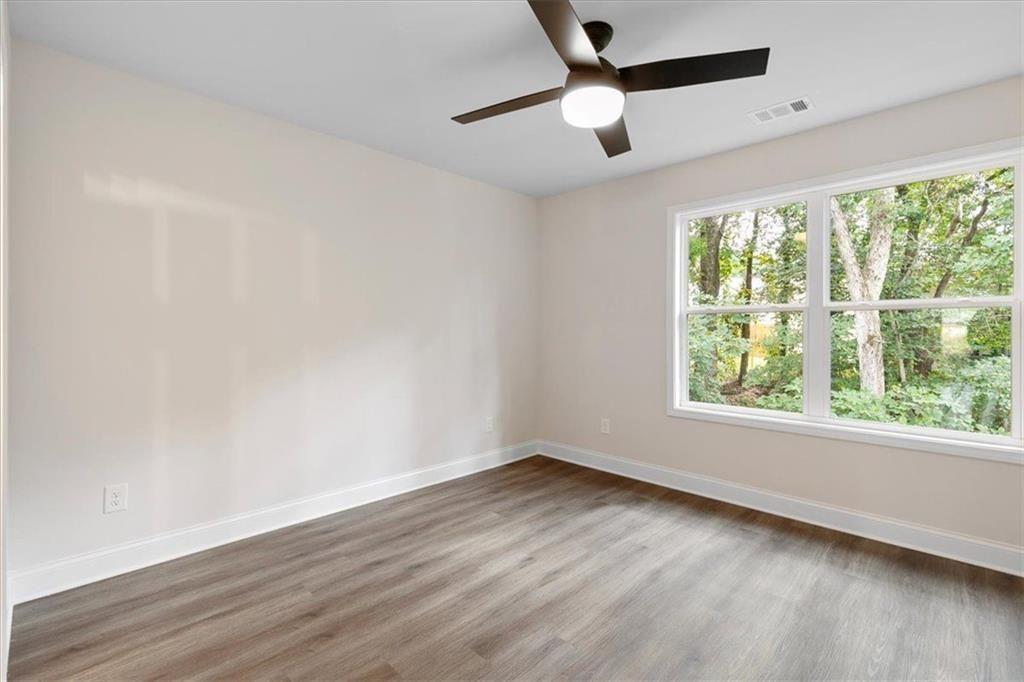 2486 Hidden Cove Court Gainesville, GA 30501 - Photo 20 of 29 an empty room with wooden floor ceiling fan and windows