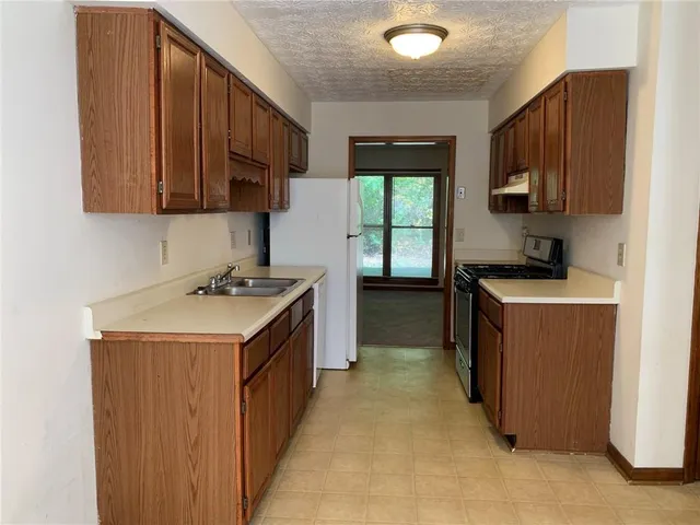 a kitchen with a sink stove top oven and cabinets