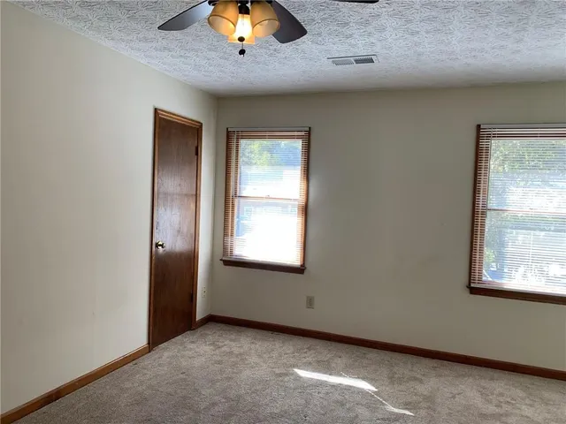 an empty room with a window and chandelier fan