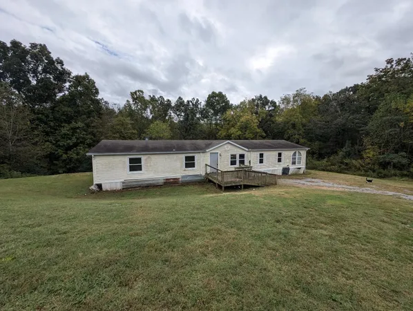 a house that is sitting in the grass with large trees