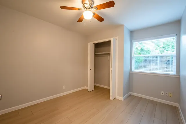an empty room with windows and fan