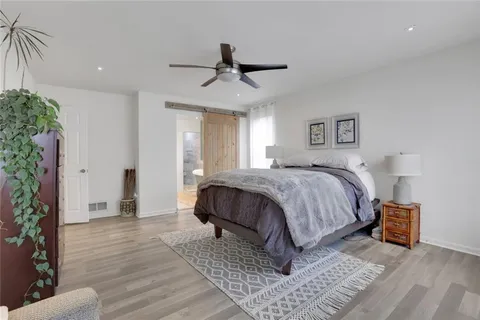a spacious bedroom with a bed a lamp and potted plant
