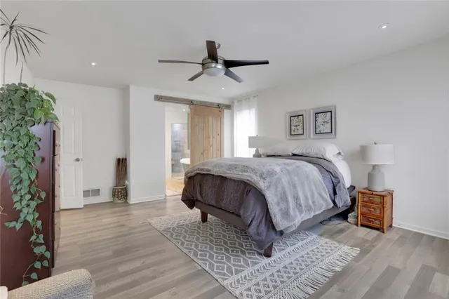 a spacious bedroom with a bed a lamp and potted plant