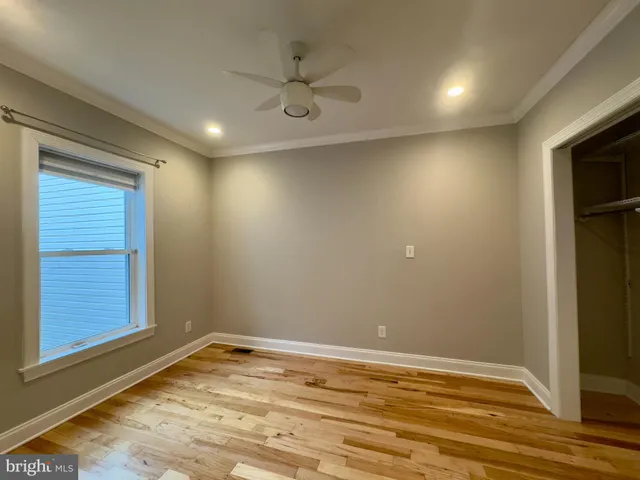 a view of empty room with wooden floor and fan