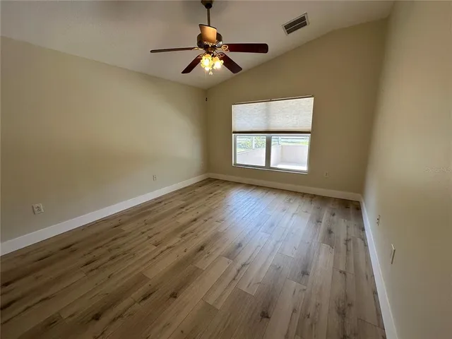 an empty room with wooden floor mirror and fan