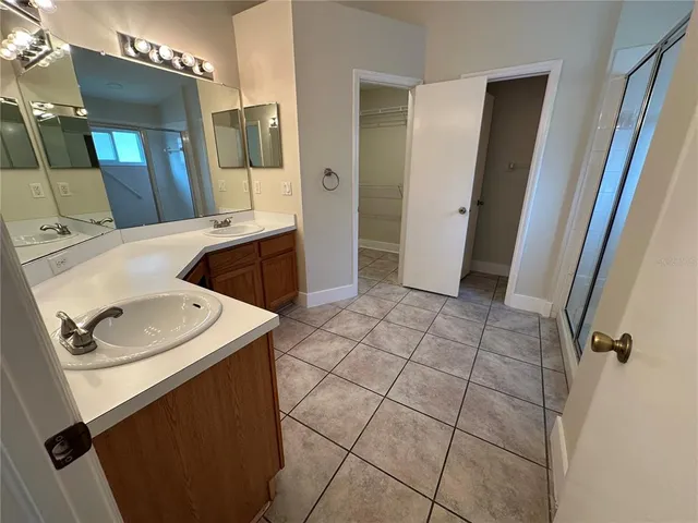 an empty room with wooden floor a ceiling fan a kitchen view and a ceiling fan