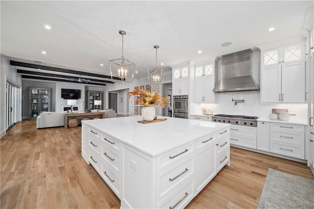 1002 Overlook Terrace Ball Ground, GA 30107 - Photo 19 of 100 a large white kitchen with kitchen island a stove a sink a refrigerator and a dining table with wooden floor