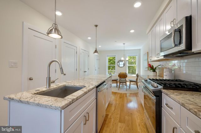 a kitchen with granite countertop a sink a counter top space stove and cabinets