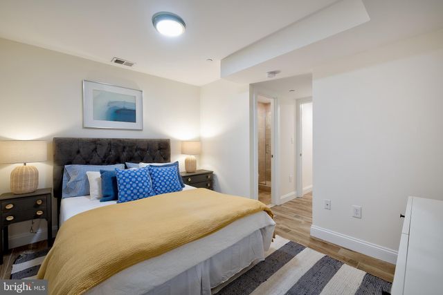 a bedroom with a large bed and a lamp on dresser