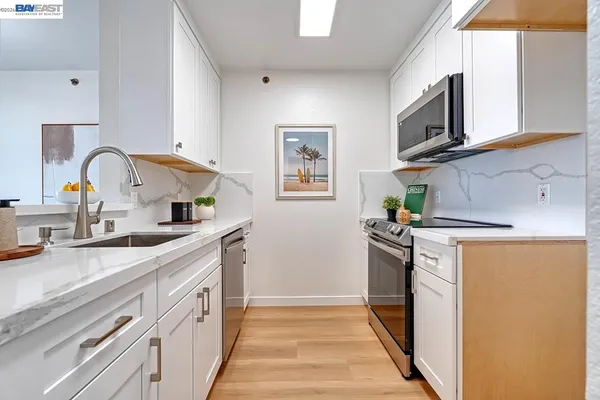 a kitchen with white cabinets and sink