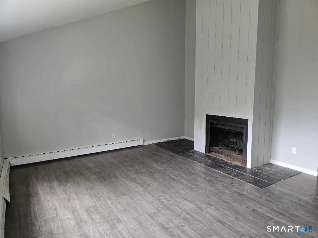 44 Armand Drive, Unit E Waterbury, CT 06708 - Photo 3 of 7 a view of an empty room with wooden floor fireplace and a window