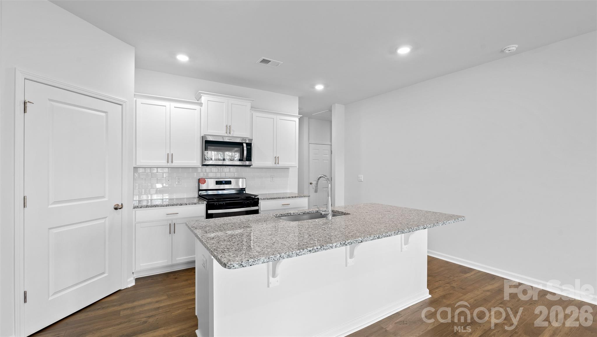 107 Bovine Br Road Fletcher, NC 28732 - Photo 6 of 20 a kitchen with granite countertop a refrigerator a stove a microwave and island with wooden floor
