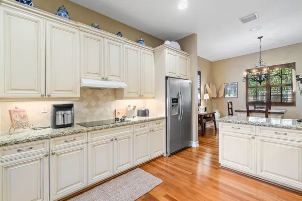 a kitchen with a sink dishwasher a refrigerator a stove and white cabinets with wooden floor