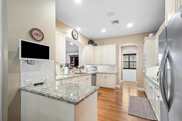 a kitchen with stainless steel appliances granite countertop a refrigerator a stove and a sink with wooden floor