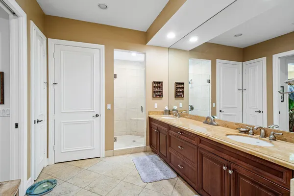 a spacious bathroom with a double vanity sink a large mirror and a shower