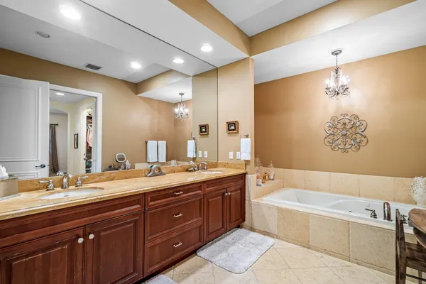 a spacious bathroom with a granite countertop double vanity sink a mirror and a bathtub