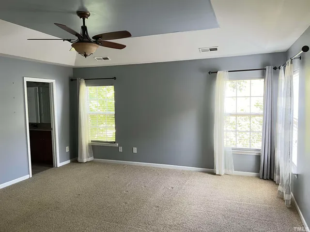 an empty room with a ceiling fan and carpet