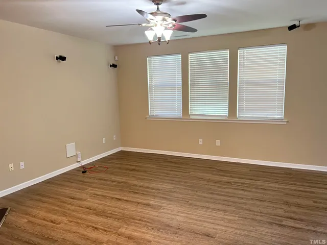 a view of an empty room with window and wooden floor