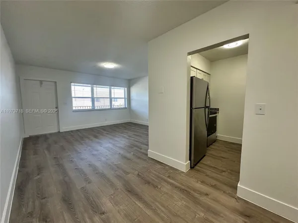 a view of empty room with wooden floor and window