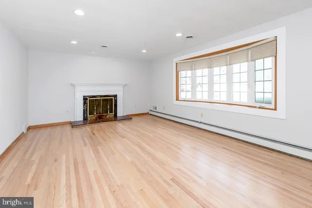 a view of empty room with wooden floor and fireplace
