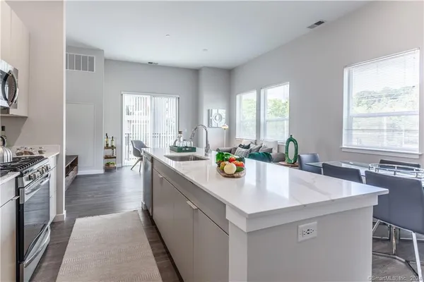 a living room with stainless steel appliances kitchen island granite countertop furniture and rug
