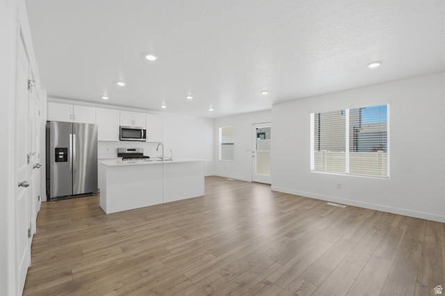 3788 South Galatia Road Magna, UT 84044 - Photo 4 of 24 Open-concept living space featuring a modern kitchen with stainless steel appliances, white cabinetry, and a central island