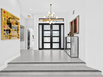 a kitchen with a stove a living room with chandelier furniture and a large window
