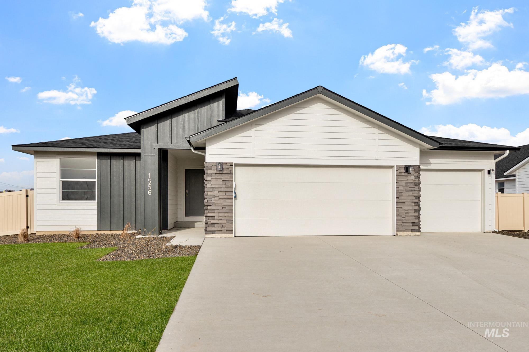 View of front of property featuring board and batten siding, concrete driveway, a garage, and stone siding