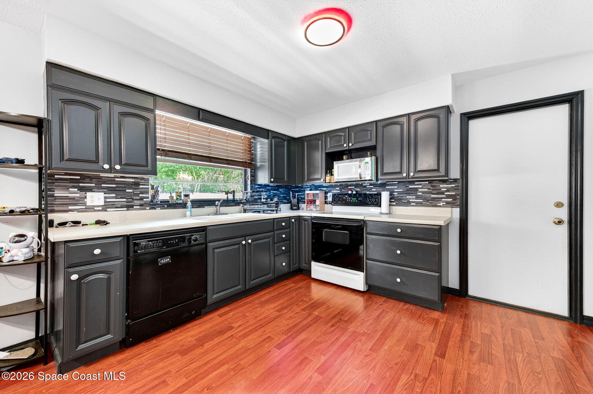 3300 Argyle Road Titusville, FL 32796 - Photo 9 of 29 a kitchen with stainless steel appliances granite countertop a stove a sink dishwasher a refrigerator and a microwave oven with wooden floor