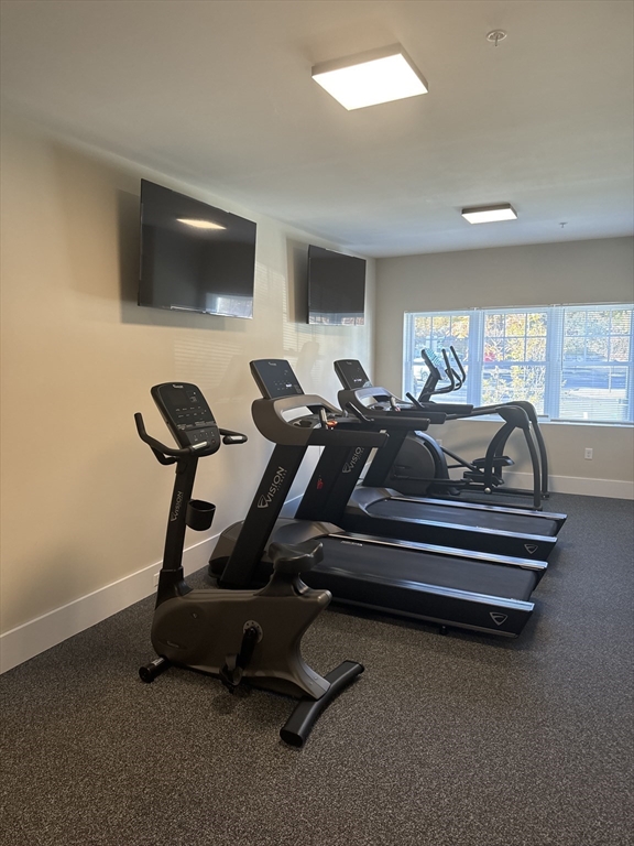 23 Prentice Street, Unit 2205 Grafton, MA 01536 - Photo 7 of 8 a room with gym equipment and a flat screen tv