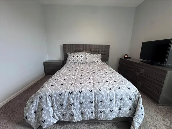 a bed sitting in a bedroom and a flat screen tv