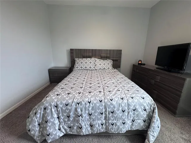 a bed sitting in a bedroom and a flat screen tv