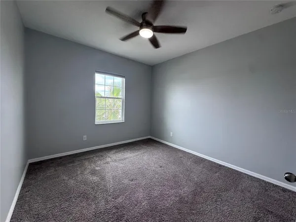 an empty room with windows and fan