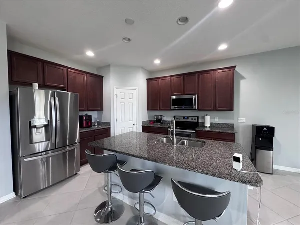 a kitchen with granite countertop a refrigerator stove microwave and cabinets