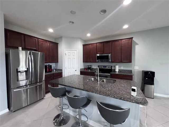 a kitchen with granite countertop a refrigerator stove microwave and cabinets
