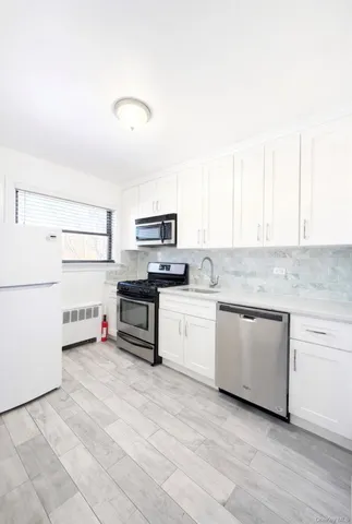 a kitchen with stainless steel appliances a stove and white cabinets