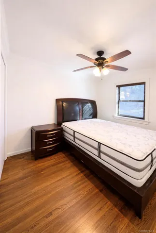 a bedroom with a bed and a ceiling fan with wooden floor