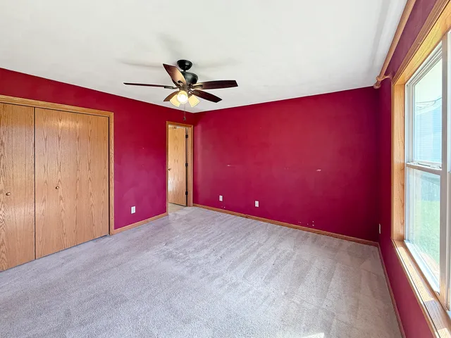 a view of a livingroom with a red ceiling fan and window