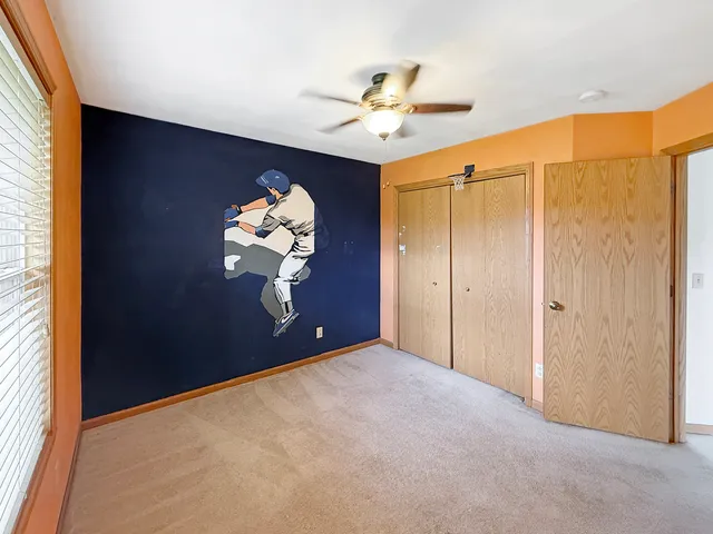 a bedroom with a chandelier fan and a window
