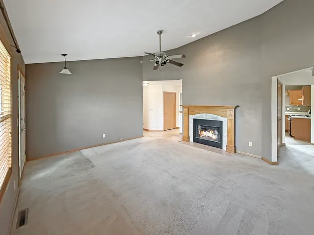 an empty room with windows and fireplace