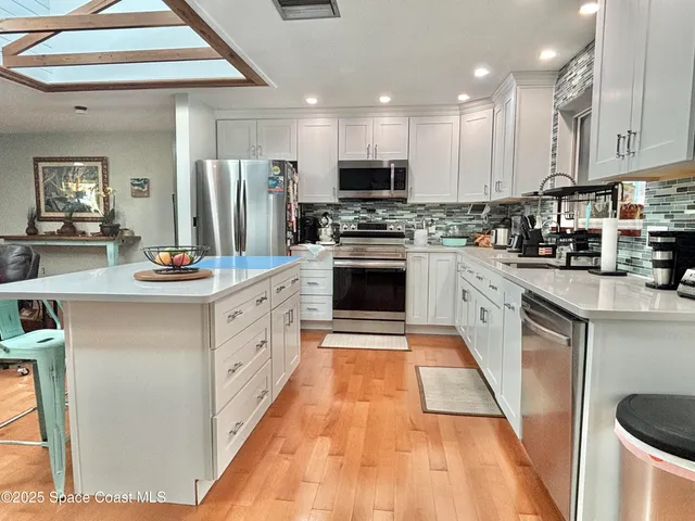 a kitchen with stainless steel appliances granite countertop a stove a sink and white cabinets