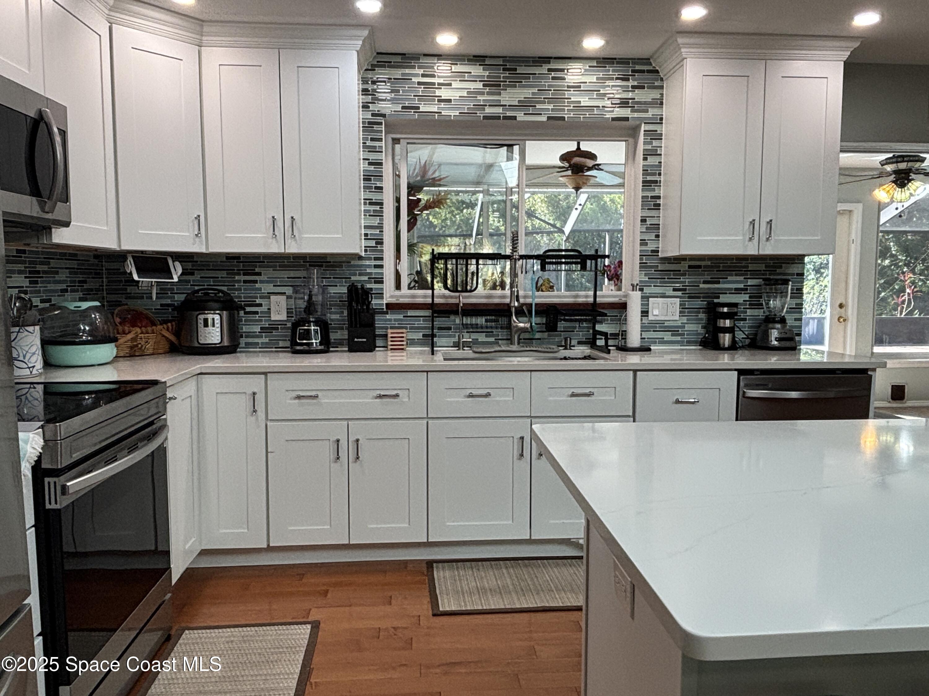 3955 Fooshe Avenue Sebastian, FL 32976 - Photo 10 of 45 a kitchen with stainless steel appliances granite countertop a stove a sink and white cabinets