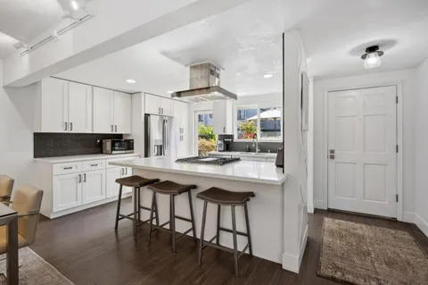 a kitchen with stainless steel appliances a dining table chairs refrigerator and sink