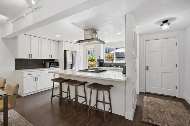 a kitchen with stainless steel appliances a dining table chairs refrigerator and sink