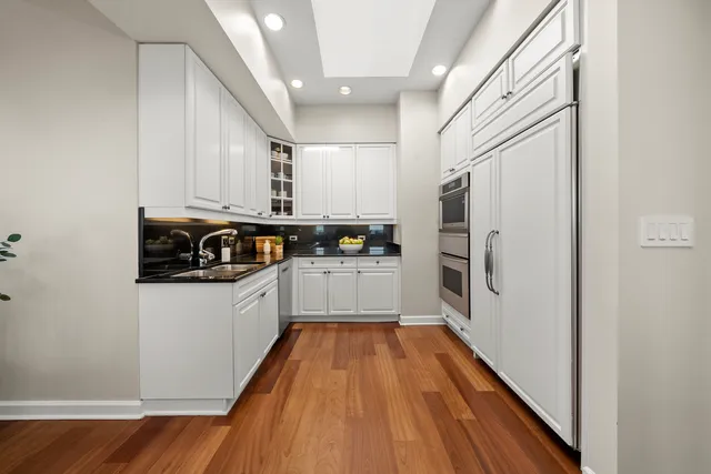 a kitchen with stainless steel appliances a refrigerator a sink and wooden floors