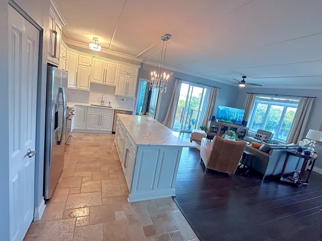 a living room with stainless steel appliances furniture a rug and a kitchen view