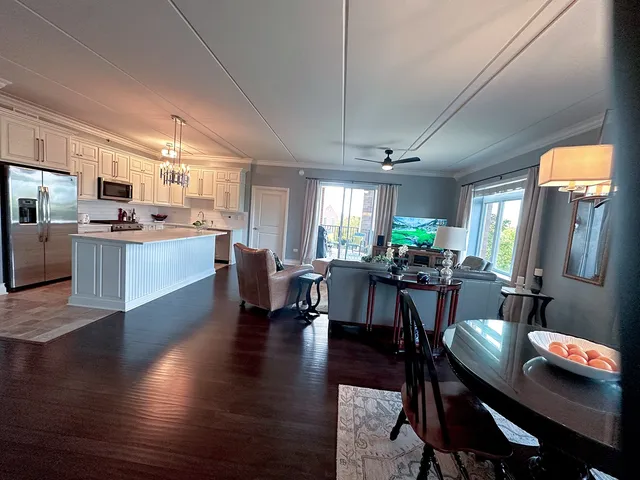a living room with furniture kitchen view and a wooden floor